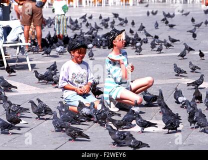 Alimentazione bambini piccioni in Piazza San Marco, Venezia, Veneto, Italia, Europa. Foto Stock