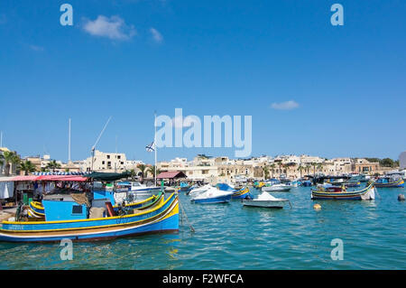 Verniciato colorato di piccole imbarcazioni ormeggiate nelle limpide acque turchesi o Marsaxlokk, Malta. Foto Stock