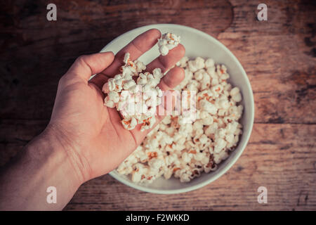 Una mano tenendo il popcorn da un recipiente grande Foto Stock