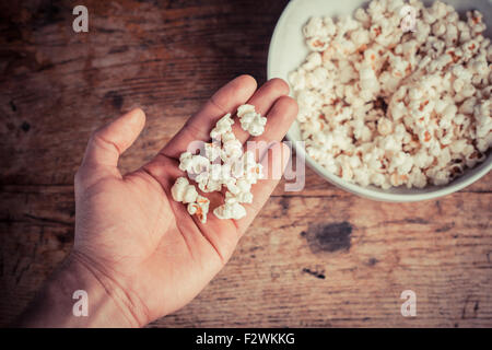 Una mano tenendo il popcorn da un recipiente grande Foto Stock