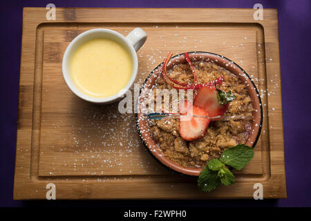 Apple Crumble dessert con crema pasticcera e fragola guarnire. Foto Stock