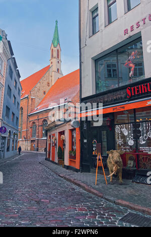 Stretta strada medievale della città vecchia di Riga (Lettonia) con caffè e ristoranti decorato per il Natale Foto Stock