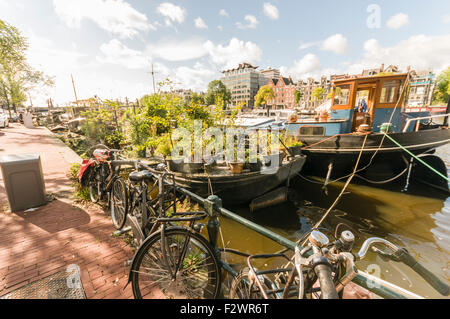 Biciclette e case galleggianti sulle rive del fiume Amstel di Amsterdam Foto Stock