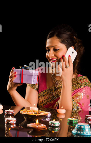 1 indian donna adulta Diwali Festival Diya e parlare per telefono cellulare e sorprendente Foto Stock