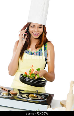 1 Adulto indiano donna casalinga Cucina Cucina e parlare per telefono cellulare Foto Stock