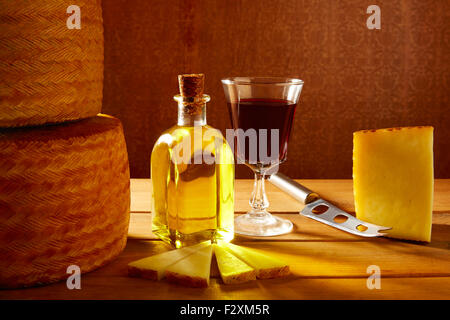 Formaggio Manchego dalla Spagna con olio di oliva e vino rosso su legno Foto Stock