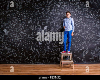 Giovani scuola bello ragazzo in piedi di fronte a grandi blackboard Foto Stock