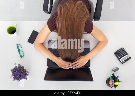 Young business woman stanco e dormire dopo la dura giornata in ufficio. Vista dall'alto. Foto Stock