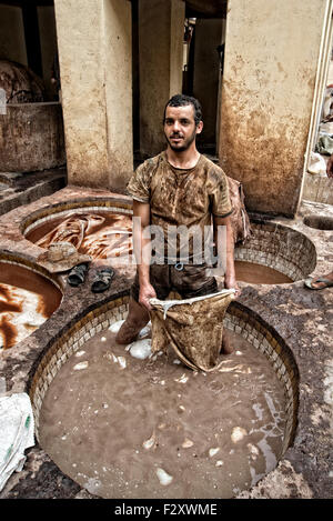 Cuoio lavoratore presso la conceria Chouarra a Fez, in Marocco, in piedi in una vasca di cuoio soluzione di rammollimento. Foto Stock