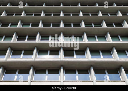 Vista prospettica della facciata di un edificio in cemento armato, con finestre che riflettono la luce diurna. Foto Stock