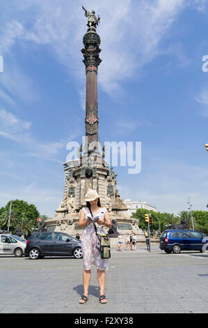 Turistico con libro guida vicino a Mirador de Colón Columbus Statua in Placa del Portal de la Pau Barcellona Spagna Foto Stock