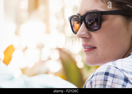 Una giovane donna che indossa gli occhiali da sole girando verso un uomo. Foto Stock