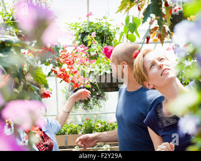 Coppia in cerca di fiori colorati e nei cestini appesi in un giardino centrale. Foto Stock