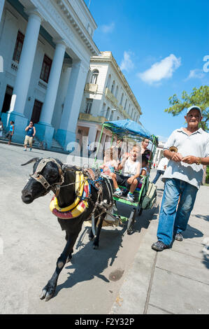 SANTA CLARA, CUBA - 28 Maggio 2011: una capra conduce un carrello pieno di bambini intorno al Parque Vidal, la piazza principale della città. Foto Stock