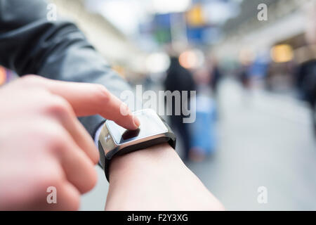 Nella postazione di sala di un uomo con il suo smartwatch. Close-up le mani Foto Stock