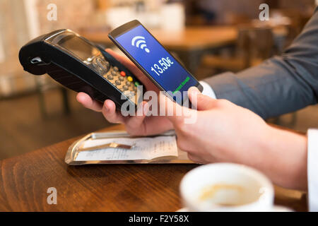 Uomo di pagare con la tecnologia NFC sul telefono cellulare, nel ristorante, bar, cafe. Euro versione francese Foto Stock