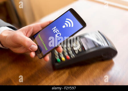 Uomo di pagare con la tecnologia NFC sul telefono cellulare. Mano di movimento Foto Stock