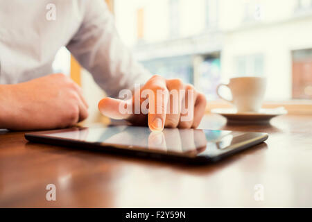 Uomo in un bar con tablet pc. Lo sfondo della finestra. Filtro vintage Foto Stock