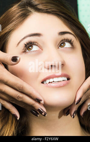 Closeup headshot brunette ottenere il trattamento di trucco dal parrucchiere professionista dando il massaggio del viso Foto Stock