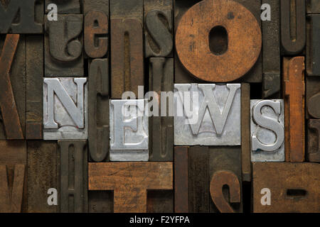 News parola fatta dalla stampa tipografica metallici isolati in un misto di lettere in legno Foto Stock