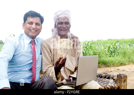 Rurale indiano Business Man e agricoltore farm laptop e il denaro che mostra Foto Stock