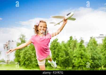 Ragazza detiene il giocattolo aereo da solo con una gamba in alto Foto Stock