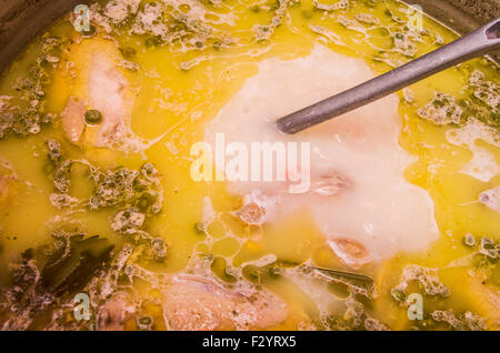 Primo piano di una deliziosa zuppa ecuadoriana con il colore giallo contenenti verdure e carne, utensile di metallo agitazione. Foto Stock