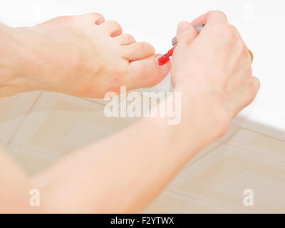 Mentre si applica il polacco a toenails Foto Stock