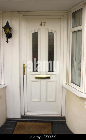 Pvc bianco porta con il numero 47 sulla porta. Una lanterna di stile è luce sulla sinistra con una piccola finestra a destra. Foto Stock