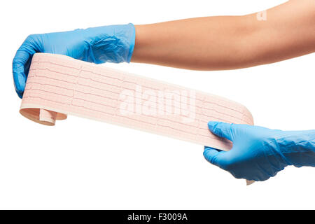 Close up medico donna con le mani in mano in blu sterilizzato guanti chirurgici con risultati ECG su un foglio di carta contro uno sfondo bianco Foto Stock