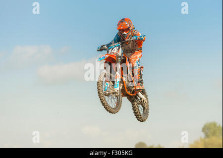 Giovane pilota di Motocross saltare in aria contro un cielo blu sullo sfondo. Foto Stock