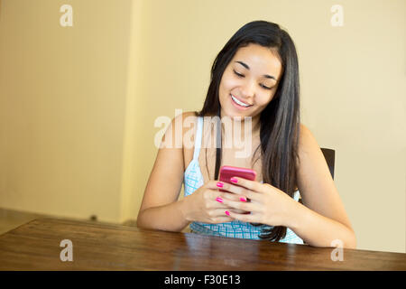 Giovane latina donna la lettura di un messaggio di testo Foto Stock