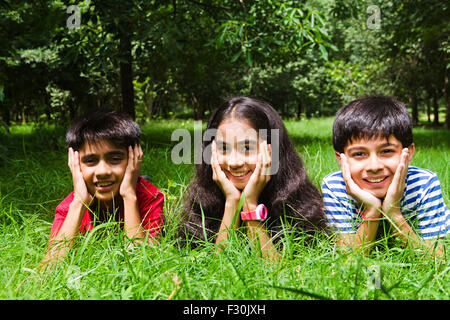 Capelli neri; nero-capelli; un abbigliamento sportivo; abiti casual; mento sulla mano; mento sulle mani; cortili; destinazioni; esaltante; GIARDINAGGIO; mezza lunghezza; le mani sul mento; Vacanze; indulgenza; indulgente; guardando la fotocamera; giacente sulla parte anteriore; la giocosità; ritratti; Foto Stock
