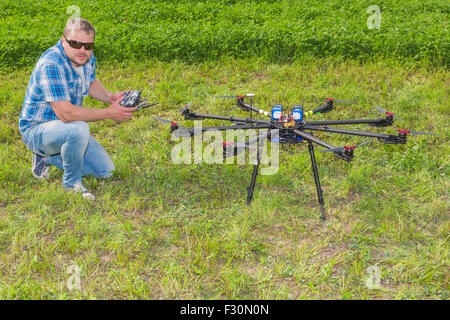 Uomo con telecomando e multicopter sul terreno Foto Stock