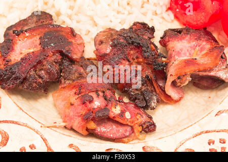 Fegato di pollo in pancetta su una piastra. Foto Stock