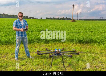 Uomo con telecomando e multicopter sul terreno Foto Stock