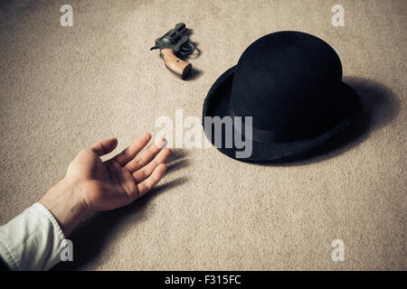 Un uomo è morto e sdraiato sul pavimento con il suo cappello e il suo revolver Foto Stock