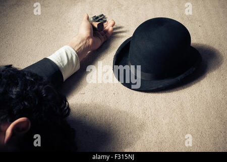 Un uomo è morto e sdraiato sul pavimento con il suo cappello e il suo revolver Foto Stock