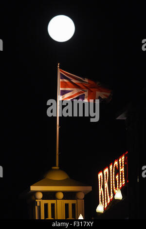 Brighton Regno Unito domenica 27 settembre 2015 - Un supermoon sorge sopra il Brighton Pier questa sera con un'eclisse lunare passando da più tardi nelle prime ore di lunedì mattina che è previsto per ruotare la luna un colore rosso come la terra getta un'ombra attraverso la luna . Fotografia scattata da Simon Dack/Alamy Live News Foto Stock