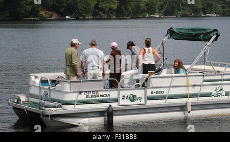 Pontoon deck barca con amici di famiglia persone a bordo. Lungo il lago di New York STATI UNITI D'AMERICA US America Adirondack State Park Foto Stock