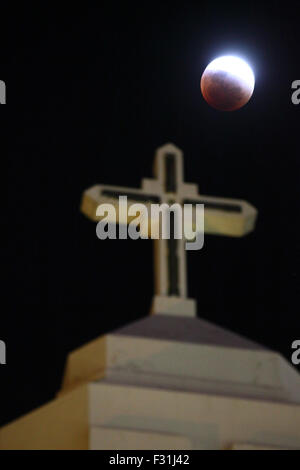 La Paz, Bolivia, 27 settembre 2015. Eclissi Parziale di luna piena sopra la croce di Maria Auxiliadora chiesa in La Paz. Settembre la luna piena è anche la più vicina supermoon del 2015, e la prima luna piena di primavera nell'emisfero meridionale. In questo mese di settembre la luna piena è chiamato anche una luna di sangue perché presenta la quarta e ultima eclissi lunare tetrad: quattro dritto eclissi totale della luna, distanziati a sei mesi lunari (lune piene) apart. Foto Stock