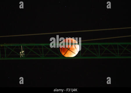 La Paz, Bolivia, 27 settembre 2015. Eclissi Parziale di luna piena al di sopra di un gantry crane in un edificio sito nel centro di La Paz. Settembre la luna piena è anche la più vicina supermoon del 2015, e la prima luna piena di primavera nell'emisfero meridionale. In questo mese di settembre la luna piena è chiamato anche una luna di sangue perché presenta la quarta e ultima eclissi lunare tetrad: quattro dritto eclissi totale della luna, distanziati a sei mesi lunari (lune piene) apart. Foto Stock