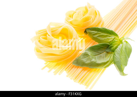 Mazzetto di materie spaghetti con le tagliatelle e foglie di basilico isolati su sfondo bianco Foto Stock