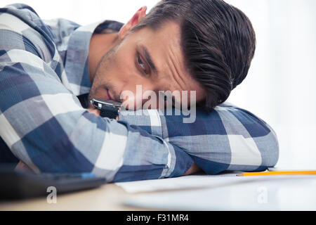 Ritratto di un triste uomo seduto al tavolo a casa Foto Stock
