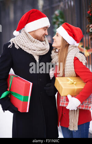 Coppia amorosa in Santa cappelli e cappotti azienda presenta per Natale Foto Stock