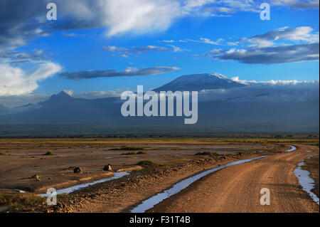 Vasto paesaggio con una strada, il Monte Kilimanjaro nella luce del mattino dietro, Amboseli, Kenya Foto Stock