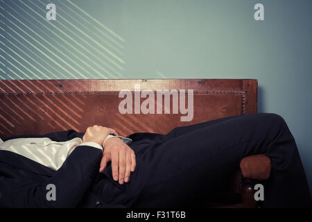 Giovane uomo è rilassante su un vecchio divano dalla finestra in una giornata di sole Foto Stock