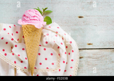 Vista superiore rosa gelato in cono di cialda su un vecchio rustico in legno vintage background. Foto Stock