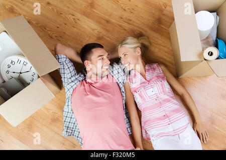 Felice coppia giacendo sul pavimento tra scatole di cartone Foto Stock