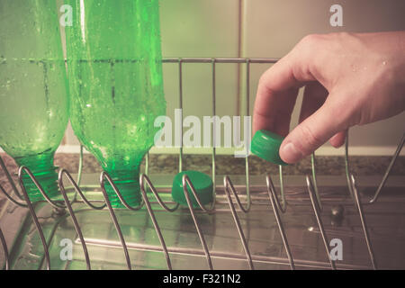 Primo piano su una giovane donna di mano come ella è il lavaggio e il riciclaggio di bottiglie in plastica Foto Stock